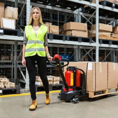 Warehouse worker dragging hand pallet truck or manual forklift with the shipment pallet unloading